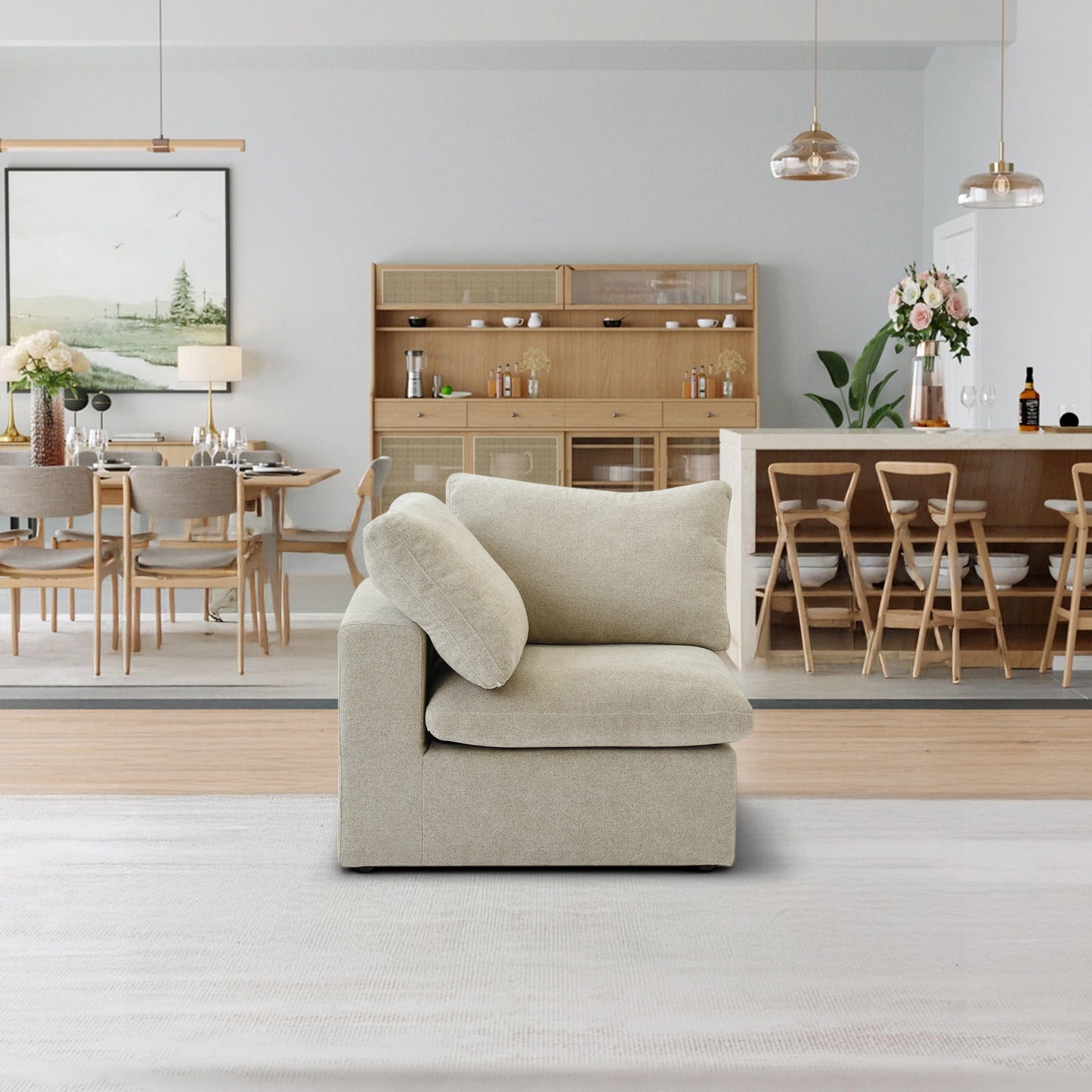 The Sofatica® Corner Cloud Couch in Beige | Premium Version is placed on a light rug in a modern open-plan dining room featuring wooden furniture, pendant lights, and a sideboard decorated with decor items and glassware.