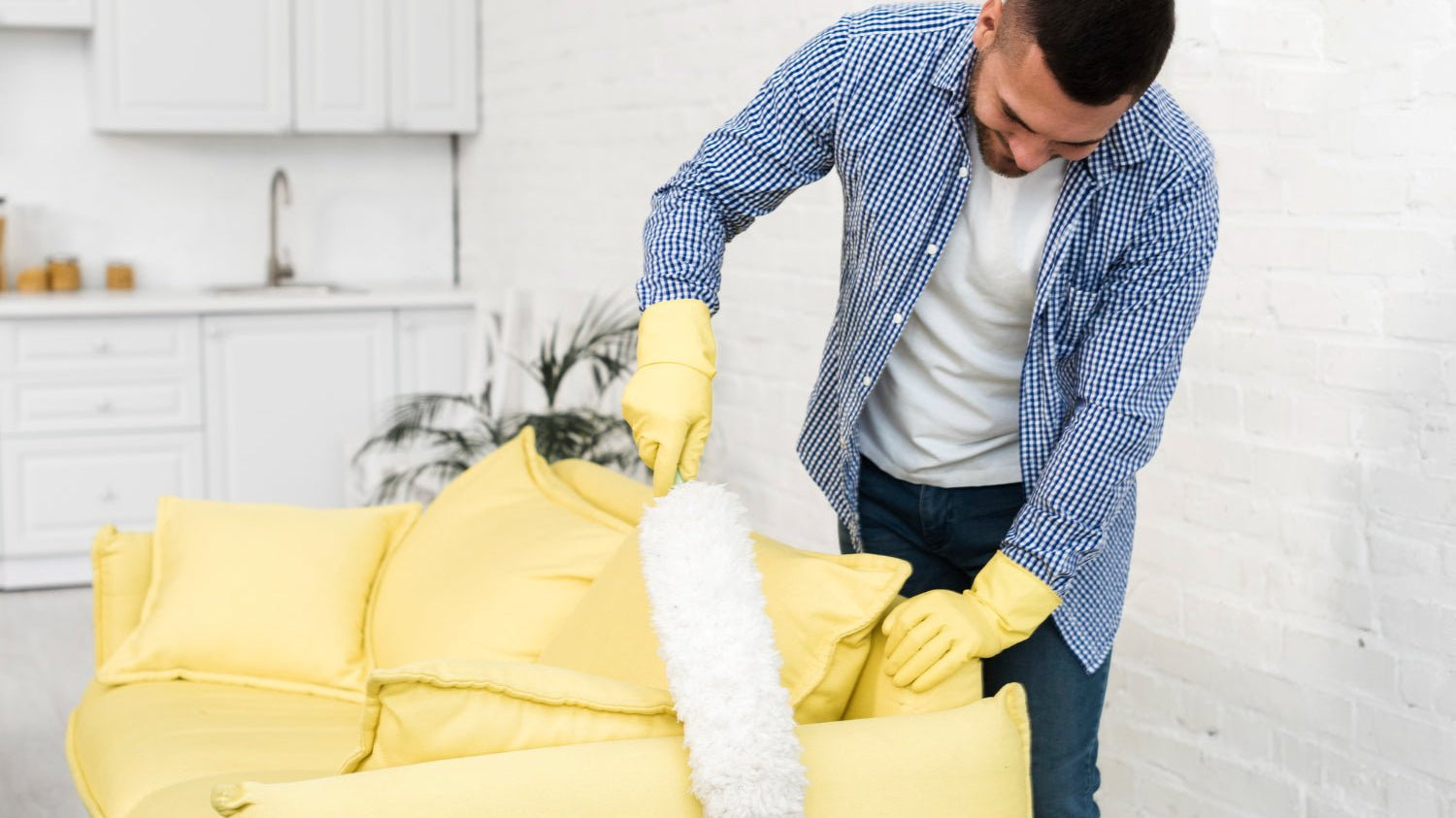 Hands cleaning a soft light sofa cushion with a microfiber cloth