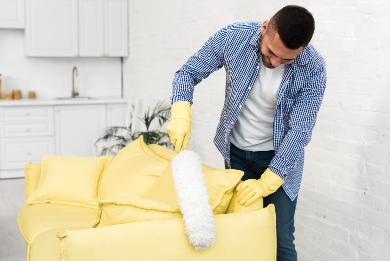 Hands cleaning a soft light sofa cushion with a microfiber cloth