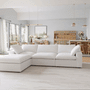 A modern living room with the CloudForm™ 3-Seater + Ottoman Modular Sofa in white, a light wood dining set, pendant lights, and large windows that fill the space with natural light.