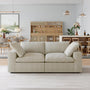 A Sofatica® Modular 2-Seater Cloud Couch in Beige | Performance Fabric sits at the center of a modern living room with wooden dining furniture, a bar cabinet, wall art, and pendant lights.