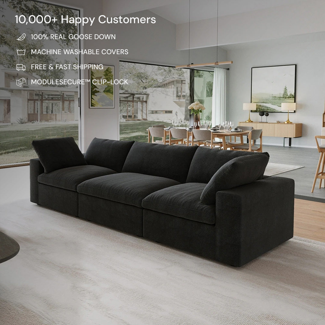 The CloudForm™ 3-Seater Modular Sofa in black sits in a modern living room with large windows and neutral decor, featuring real goose down fill and removable, machine-washable fabric covers.