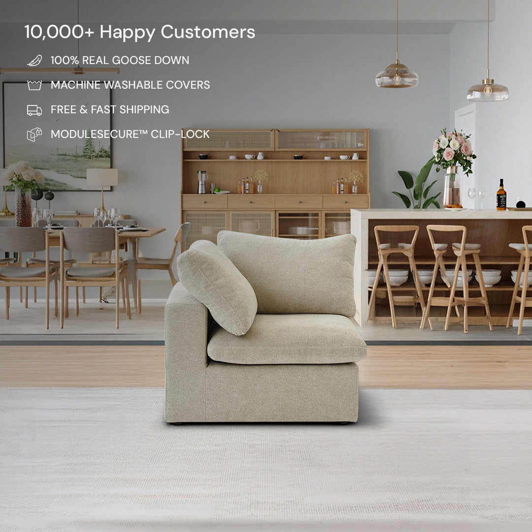 A CloudForm™ Corner Modular Sofa in beige with removable fabric covers sits on a light rug in a modern dining room featuring wooden furniture and floral décor; product features are listed above the sofa.