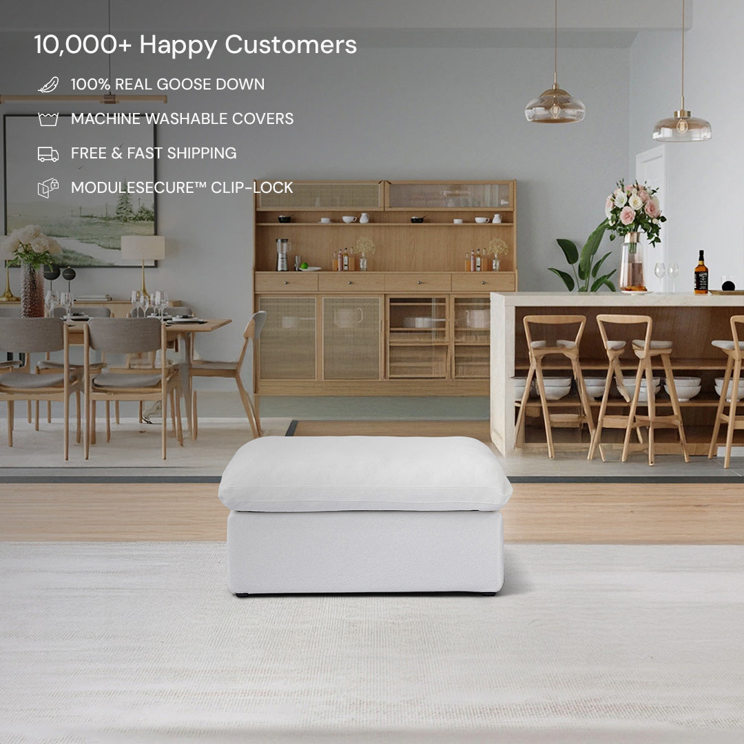 The CloudForm™ Ottoman Modular Sofa in white with removable fabric covers is placed on a rug in a modern dining room featuring wooden furniture, flowers, and product features displayed above.